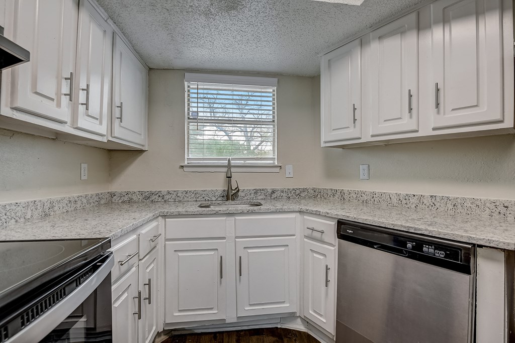 a kitchen with white cabinets and granite counter tops