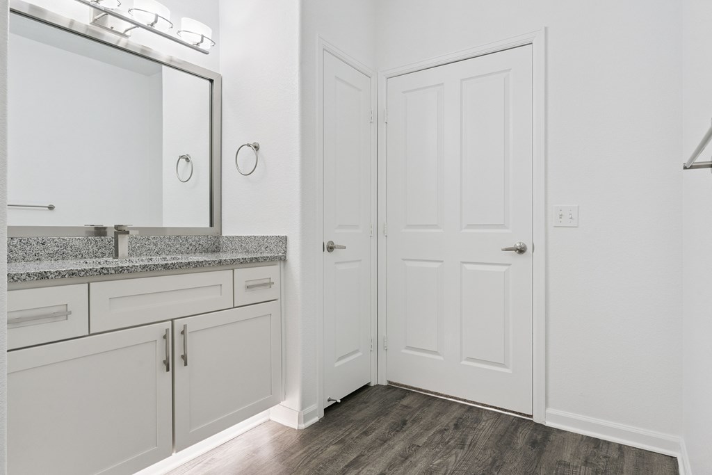 A white bathroom with a vanity and a door.