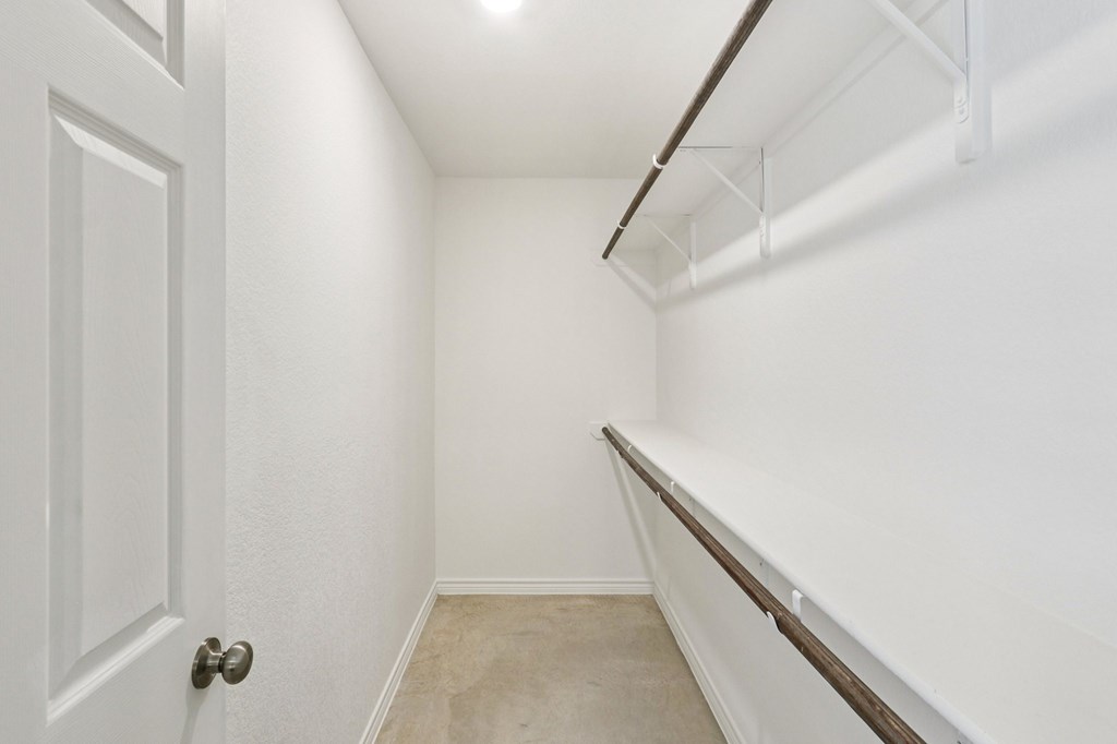 A white door is on the left side of a hallway with a white wall and a brown trim.