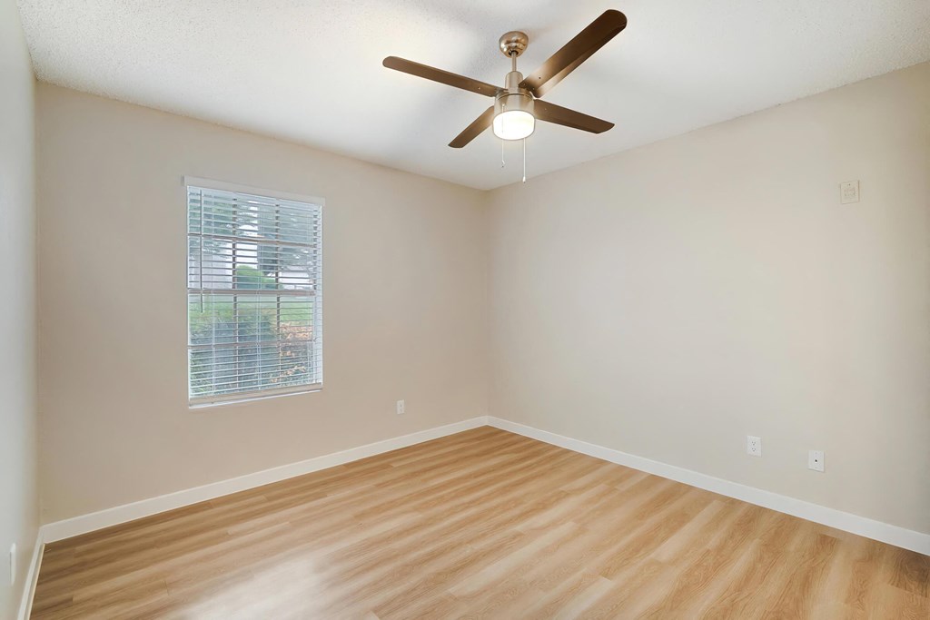 an empty room with a ceiling fan and a window
