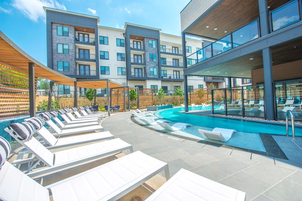 a pool with lounge chairs and a building in the background