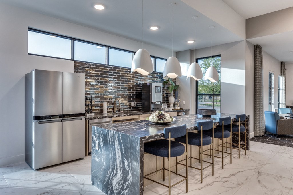 a kitchen with stainless steel appliances and a marble counter top and blue chairs