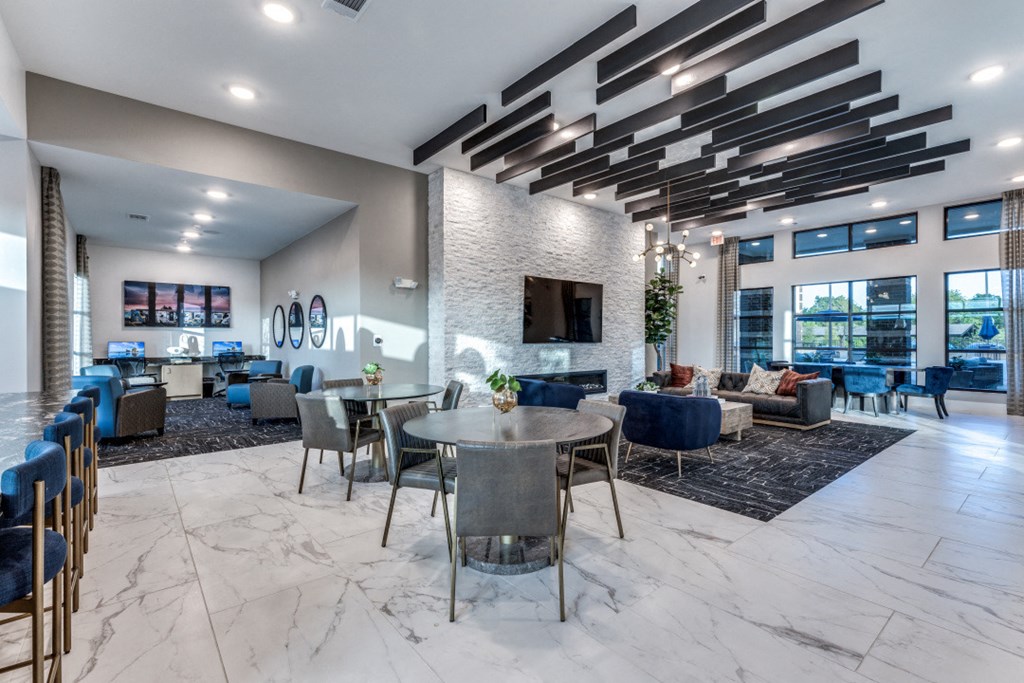 a communal area with tables and chairs and a living room with a fireplace