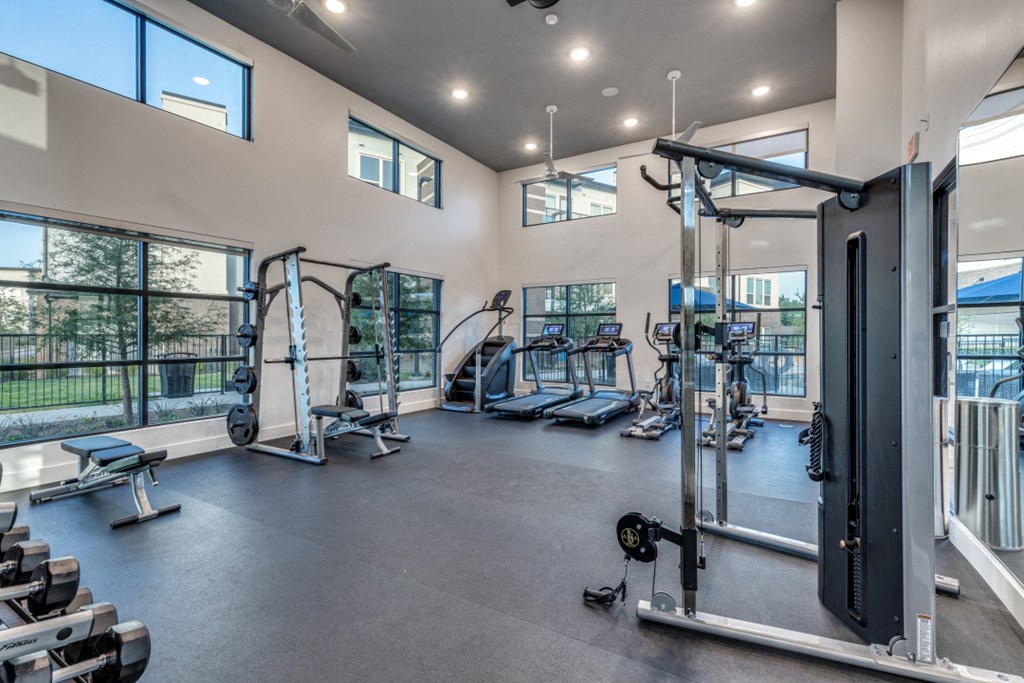 a gym with weights and cardio equipment and large windows