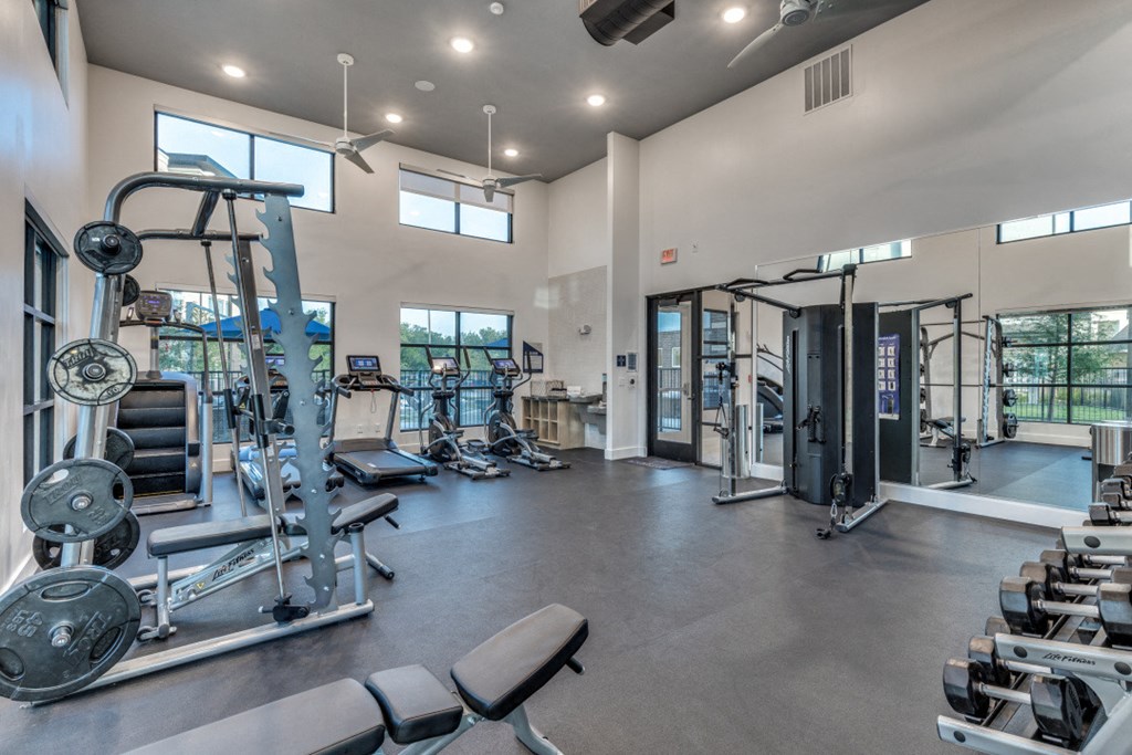 a gym with weights and cardio equipment and windows