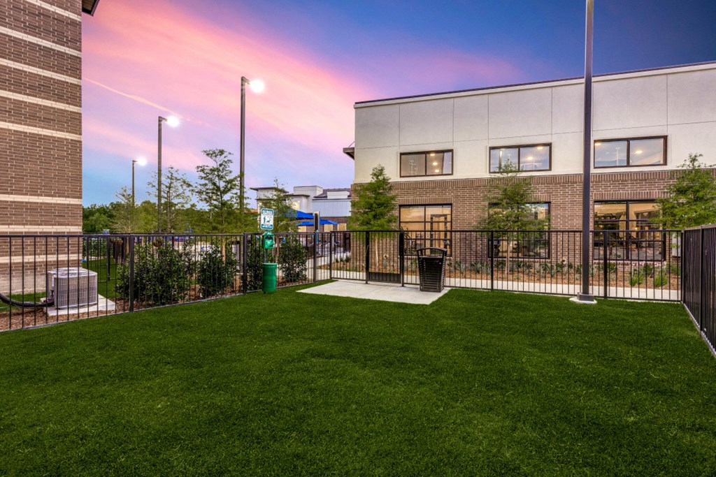 the yard of a building with green grass and a fence