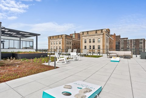 a rooftop patio with chairs and tables and buildings in the background