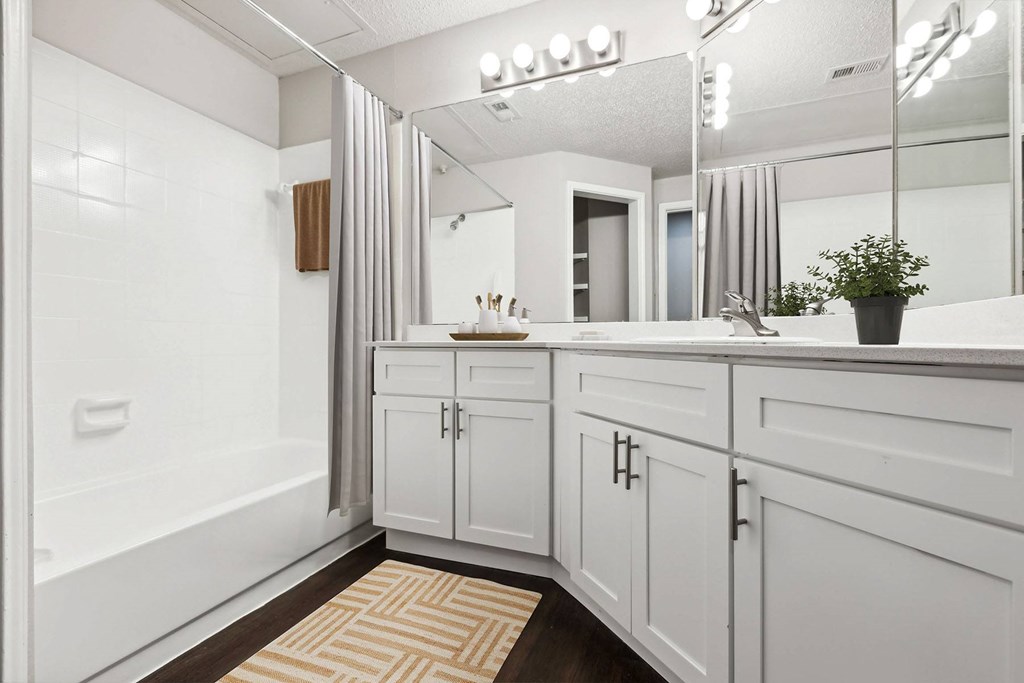 A bathroom with white cabinets and a mirror above the sink.