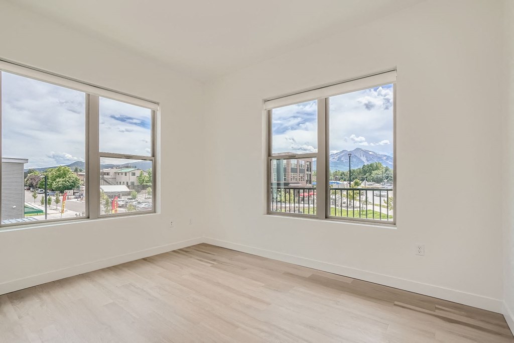 a bedroom with three windows and a view of the mountains