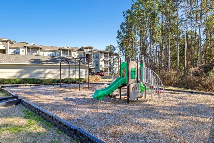 a playground with a slide and swing set in front of a house