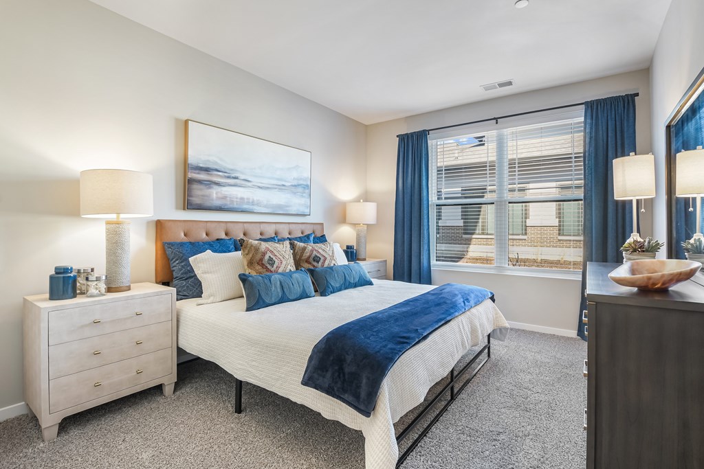 A bedroom with a large bed, a nightstand, and a painting on the wall.