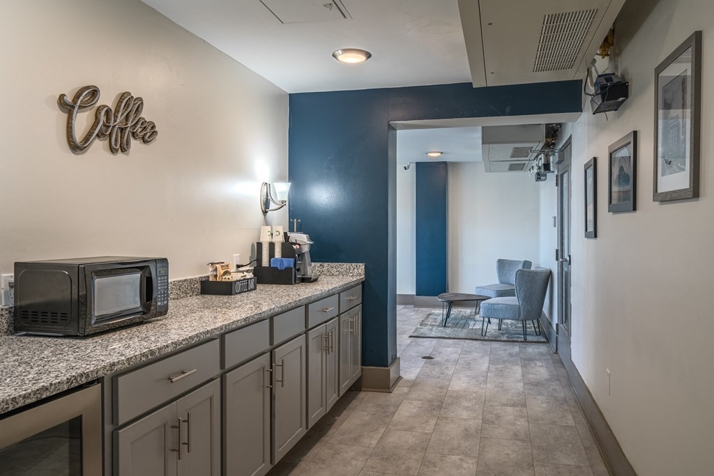 a kitchen with granite counter tops and a microwave and a hallway to a living room