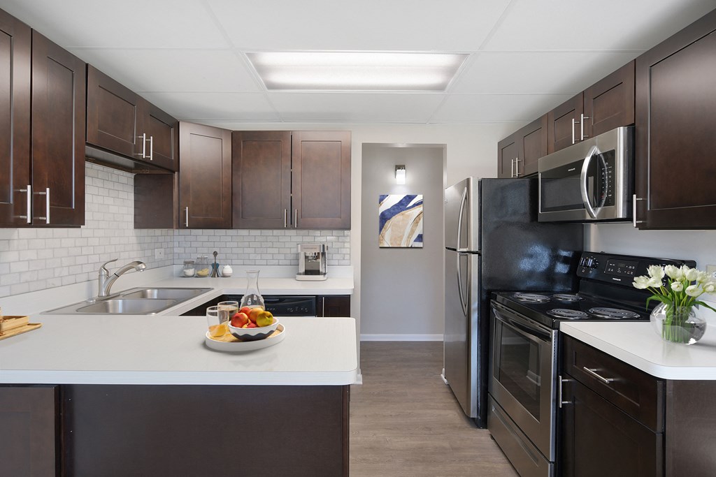 a kitchen with stainless steel appliances and a white counter top with a bowl of fruit