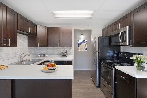 a kitchen with stainless steel appliances and a white counter top with a bowl of fruit