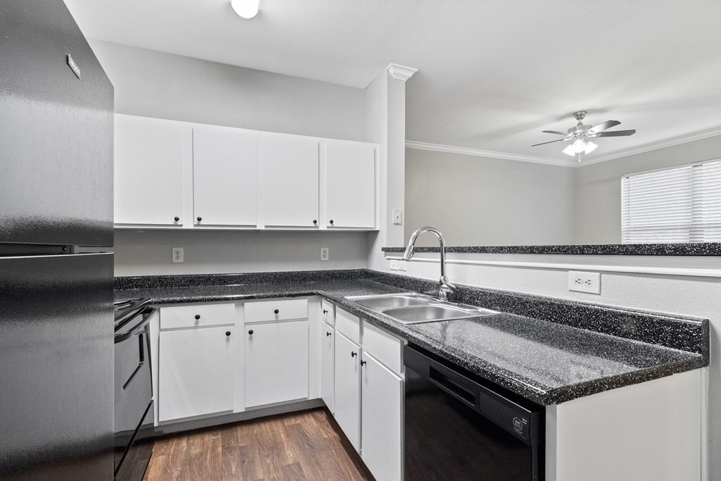 a kitchen with white cabinets and granite counter tops and a sink
