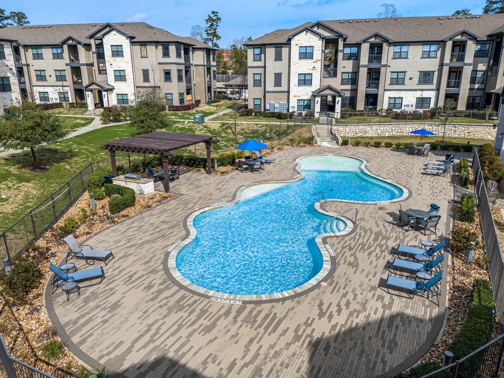 A large swimming pool with a wooden deck and lounge chairs.