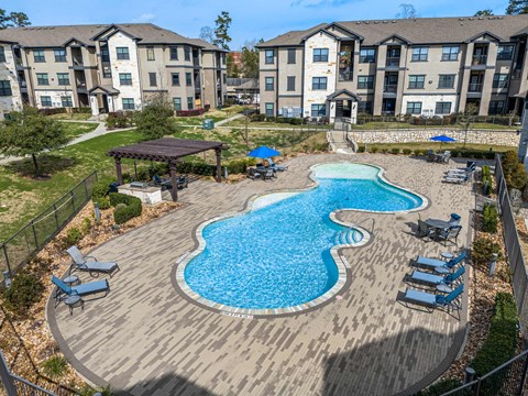 A large swimming pool with a wooden deck and lounge chairs.