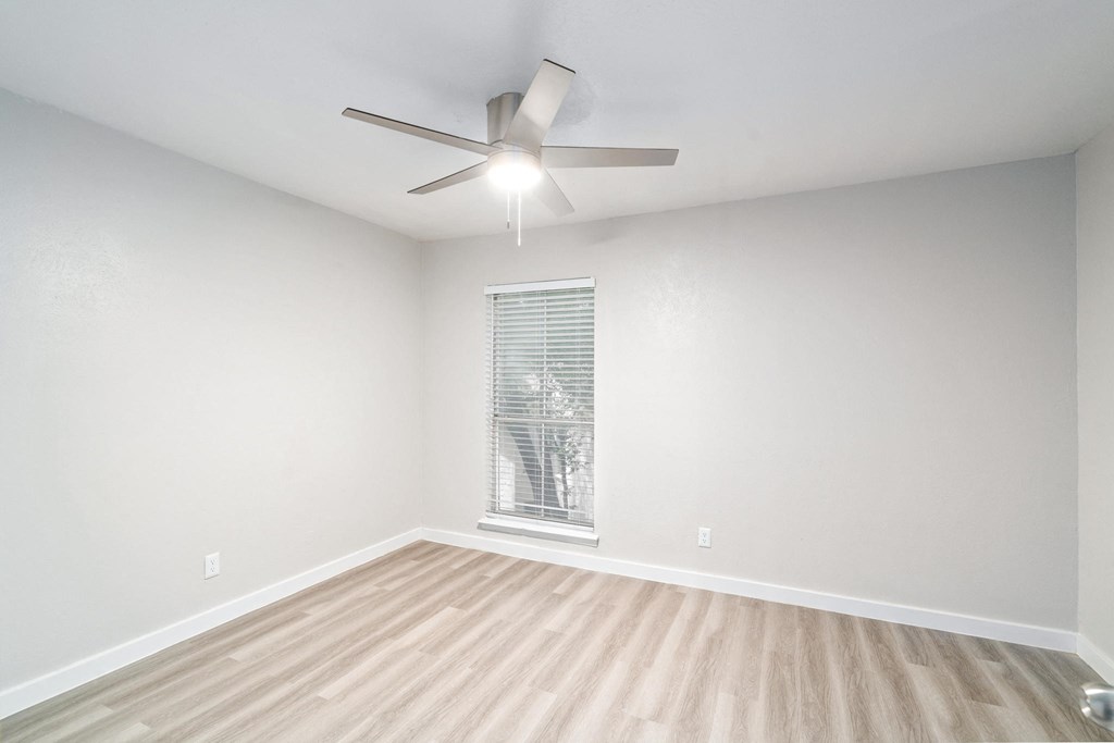 an empty room with a ceiling fan and a window