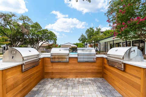 two bbq grills in the backyard of a home with a pool in the background