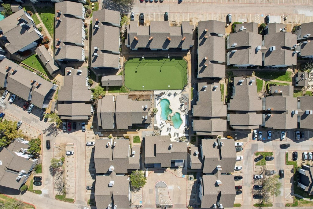 A bird's eye view of a residential area with houses and a green lawn.