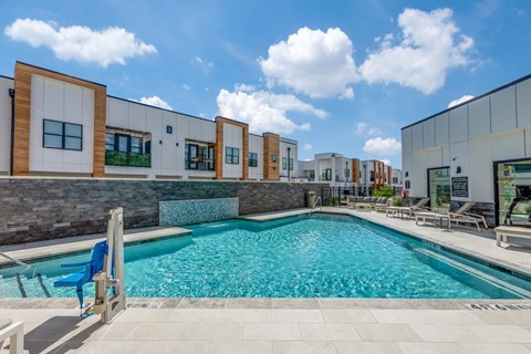 A swimming pool in front of a building with a blue chair.