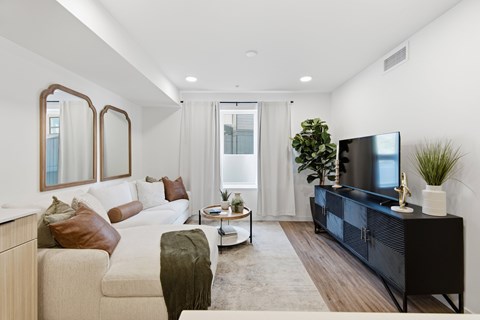 A modern living room with a white couch, a black entertainment center, and a large window.