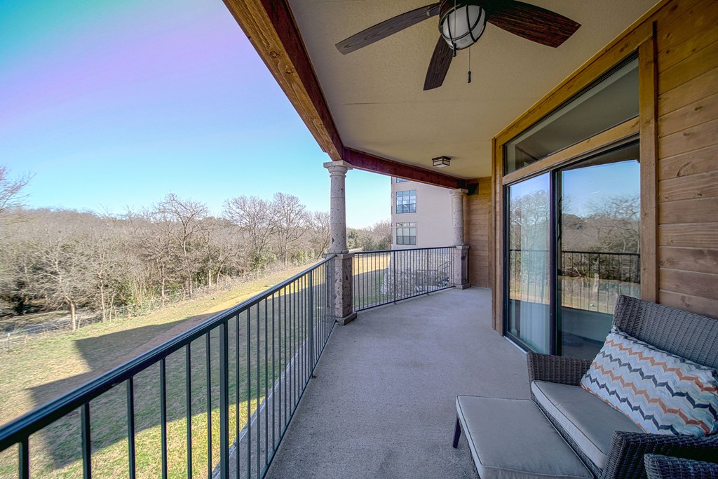 the view from the balcony of a home with a large window and a couch