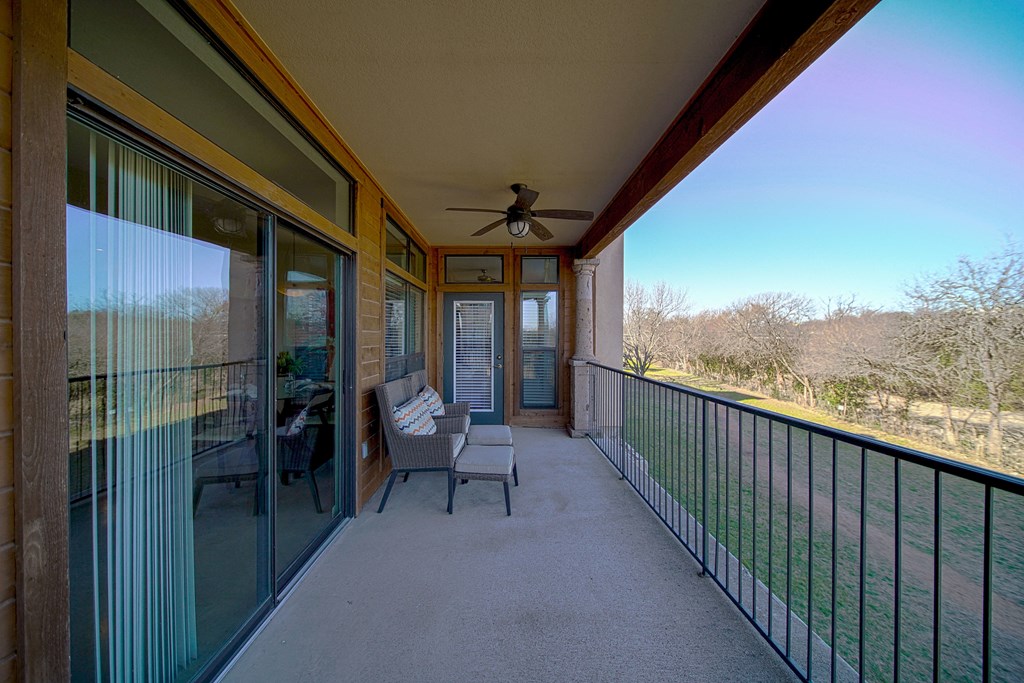 a covered porch with chairs and a table and a ceiling fan