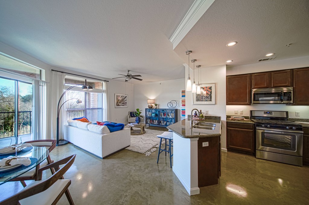 furnished living room and kitchen with stainless steel appliances and a large window