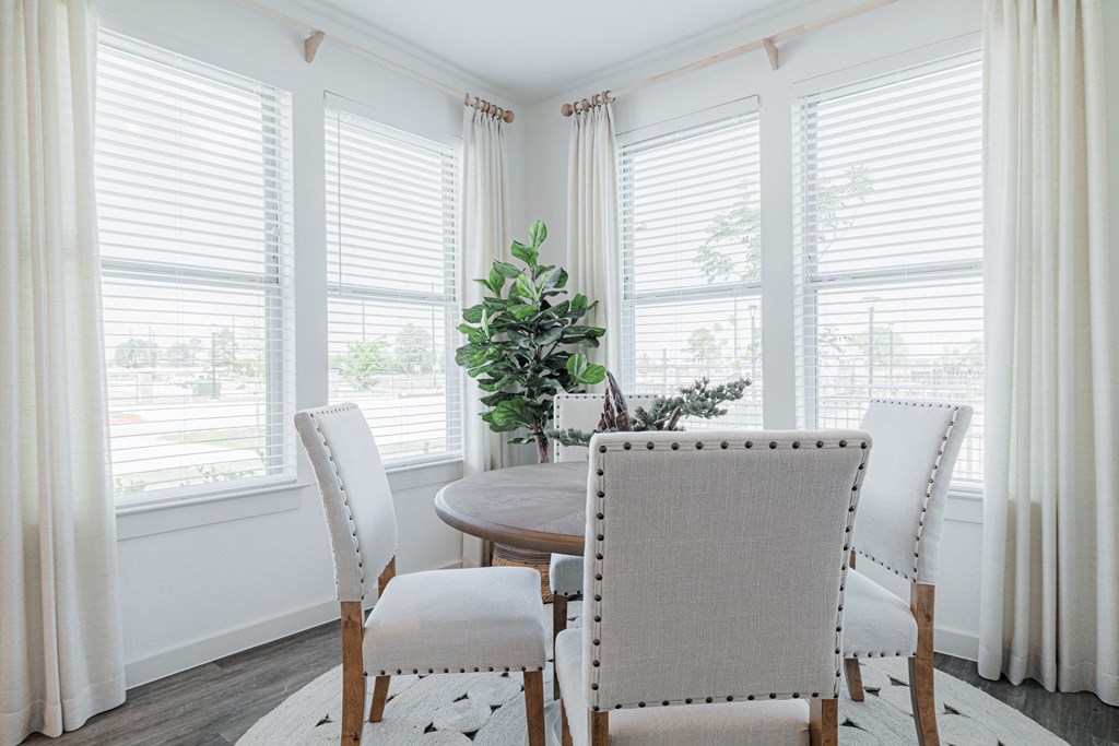 a dining room with white walls and a wooden table with white chairs