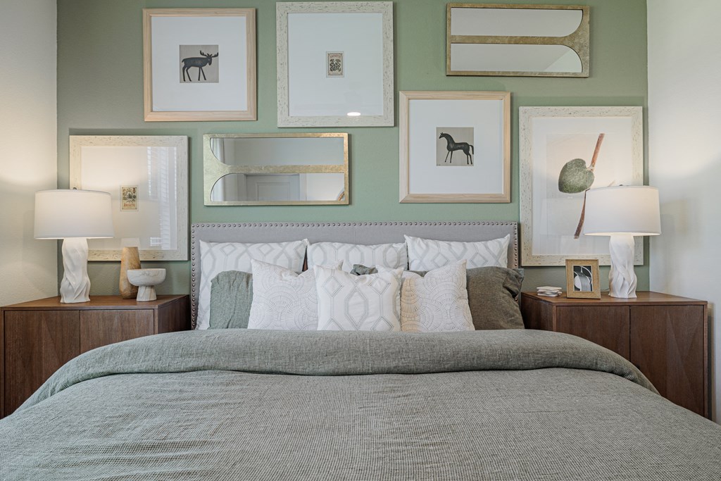 a bedroom with green walls and a bed with white and grey bedding