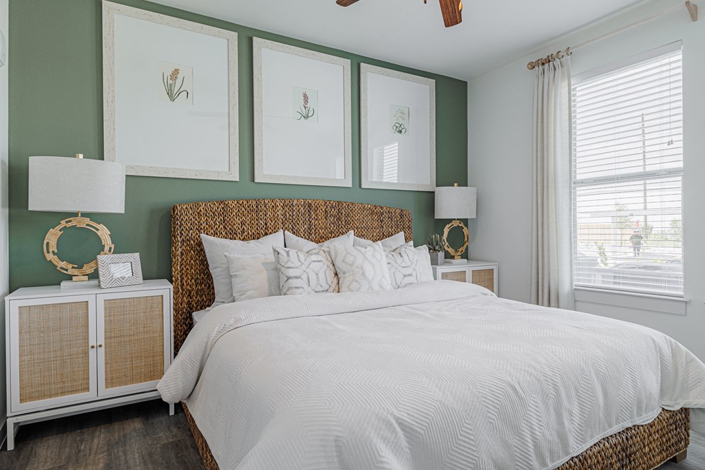 a bedroom with green walls and a white bedspread and rattan headboard