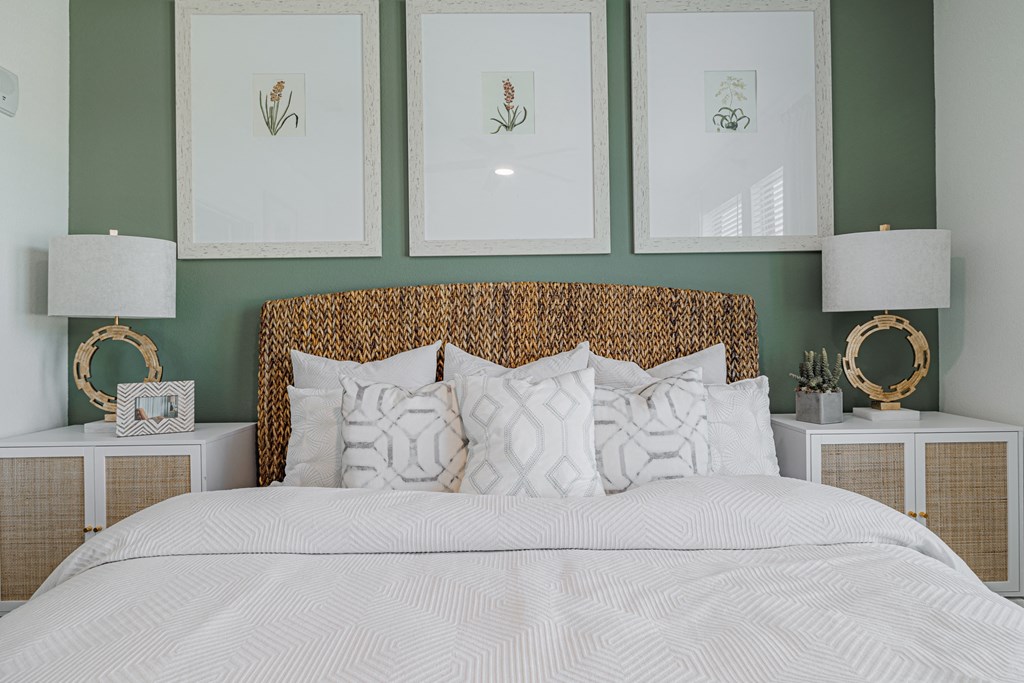 a bedroom with green walls and a white bedspread and rattan headboard