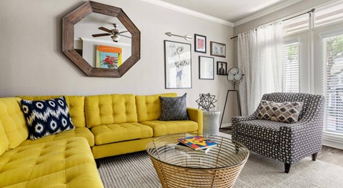 A yellow sofa with a wicker coffee table in front of it.