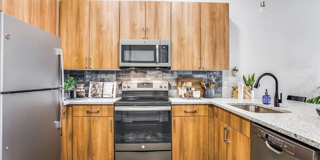 A kitchen with wooden cabinets and a stainless steel refrigerator.