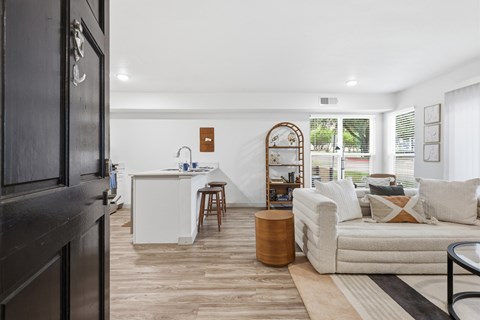 A modern living room with a white sofa and a wooden floor.