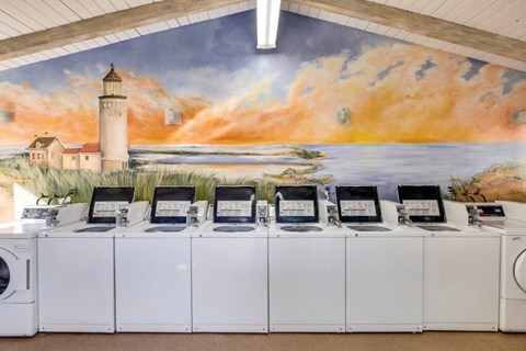A row of computers are lined up in front of a mural.