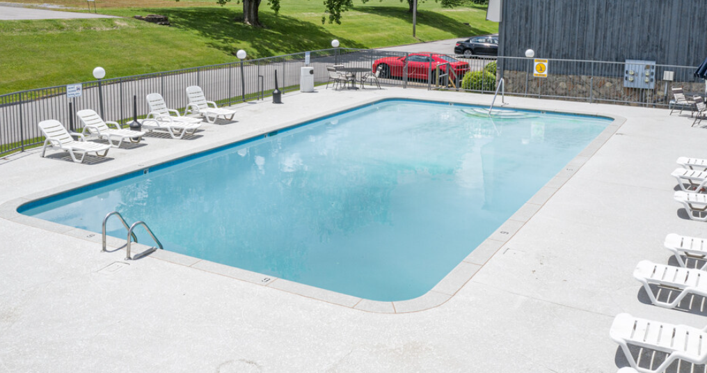 a swimming pool with chaise lounge chairs and a grassy area in the background