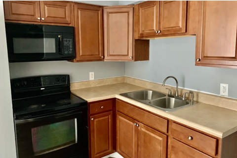 a kitchen with wood cabinets and black appliances and a sink