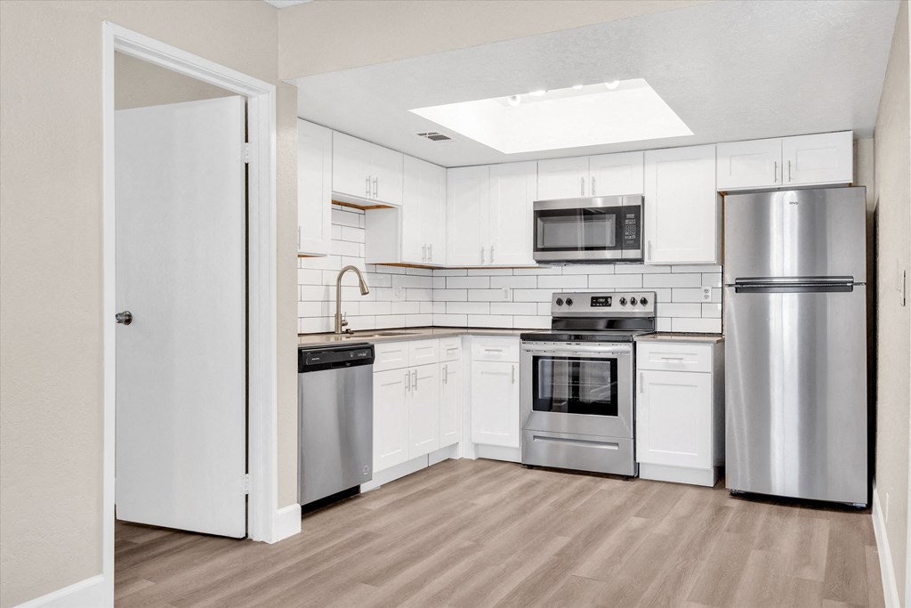 a kitchen with white cabinets and stainless steel appliances