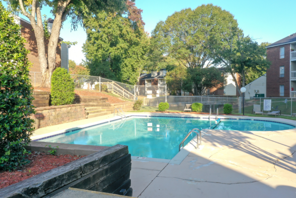 a swimming pool in front of a house with a fence