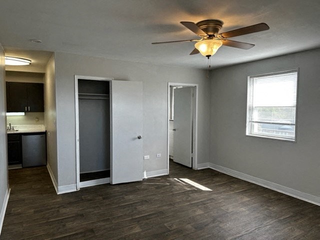 an empty living room with a ceiling fan and a kitchen