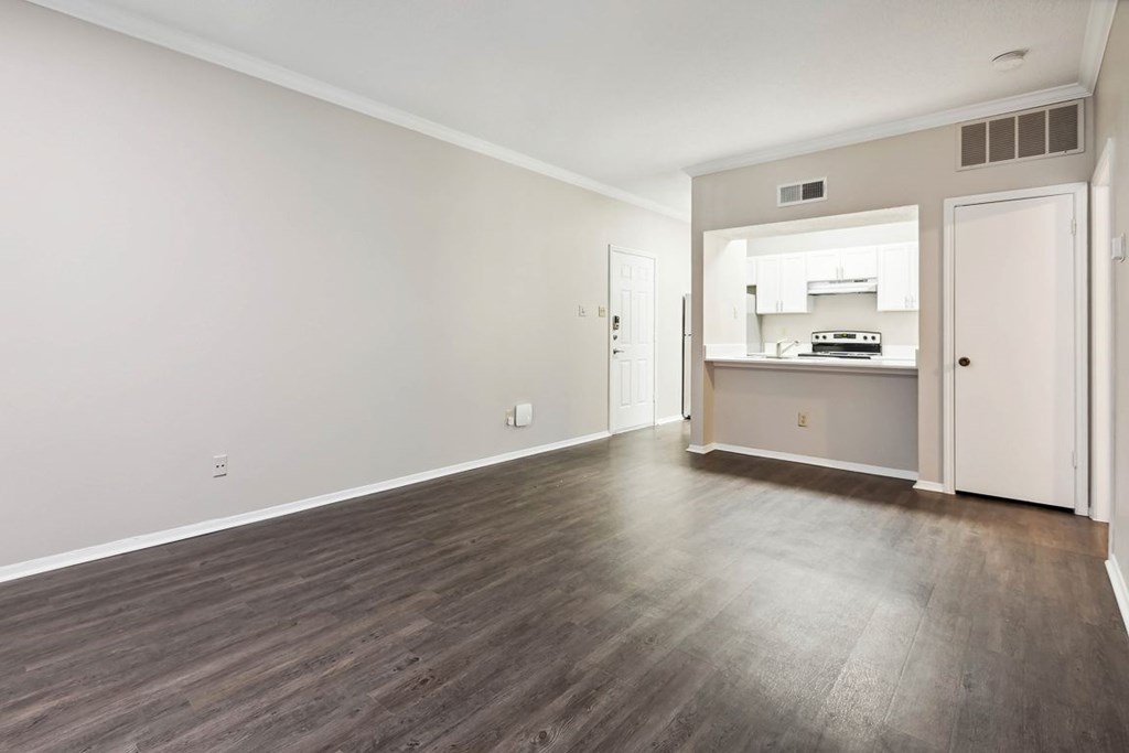 A room with a kitchenette in the back and a door on the right.