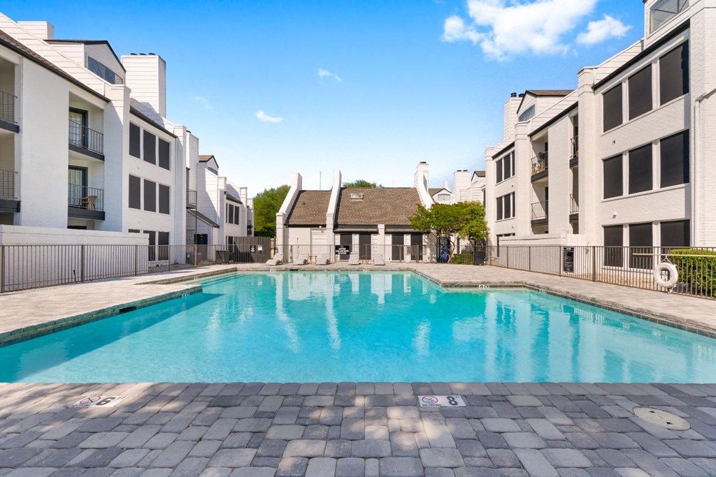 a swimming pool between two buildings with a blue sky in the background