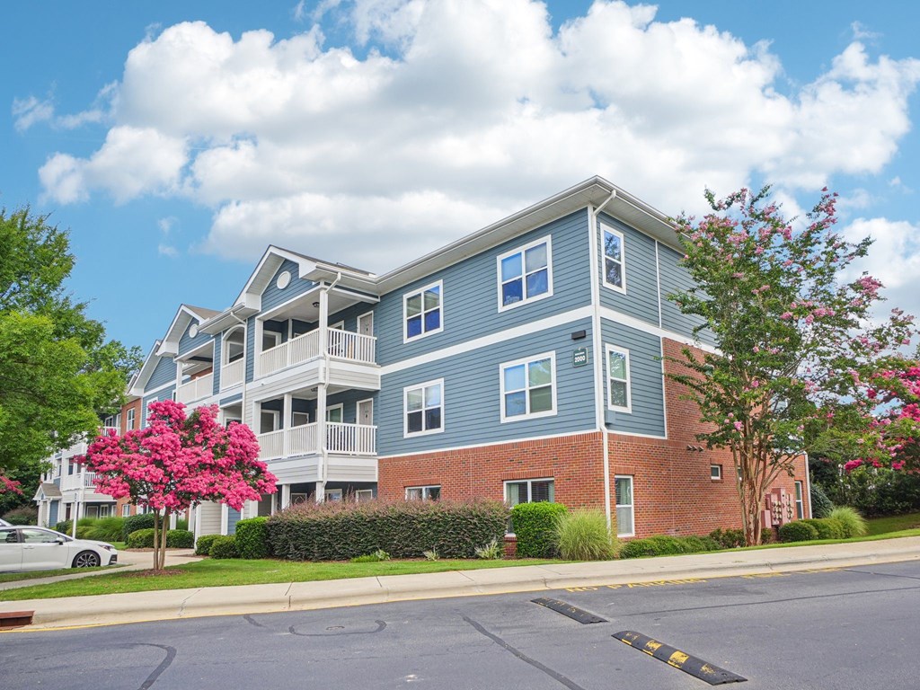 A large apartment building with a blue and grey exterior and a red brick building in the front.