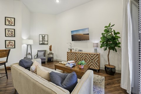 A living room with a beige couch, a wooden coffee table, and a painting on the wall.