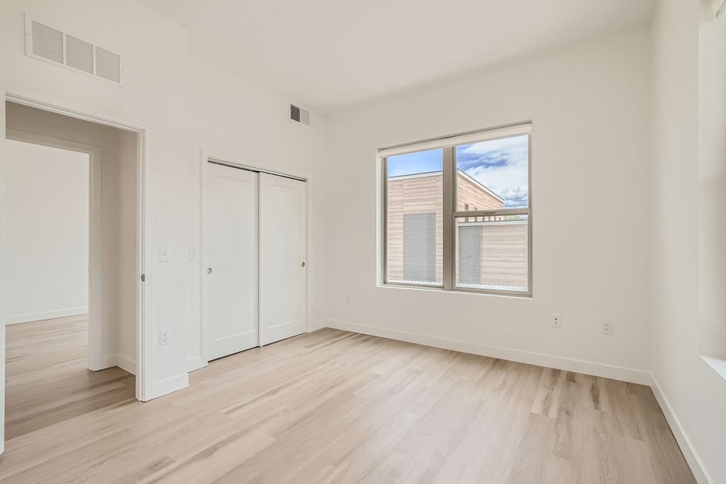 a bedroom with hardwood floors and white walls