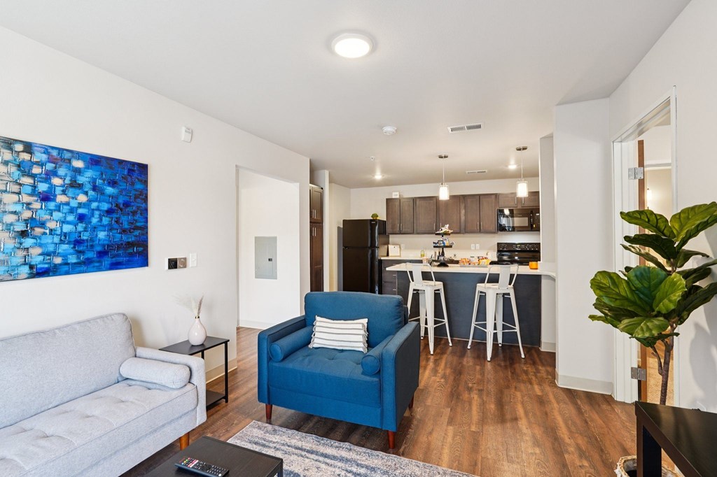 A blue chair sits in a living room with a grey couch.