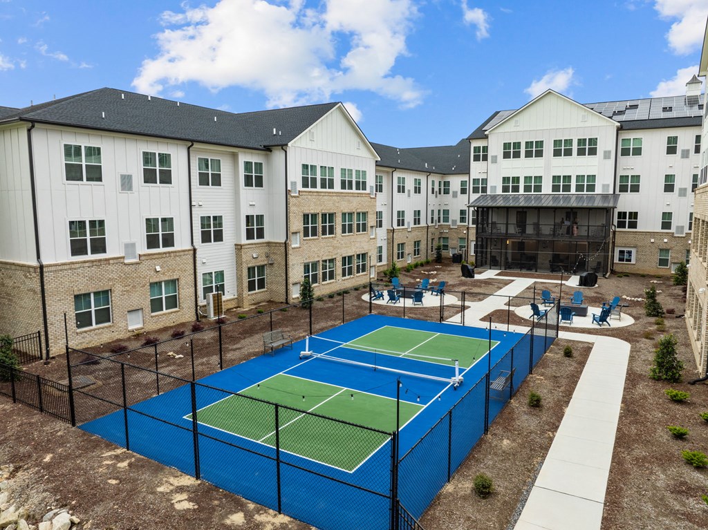 an outdoor tennis court with apartments in the background
