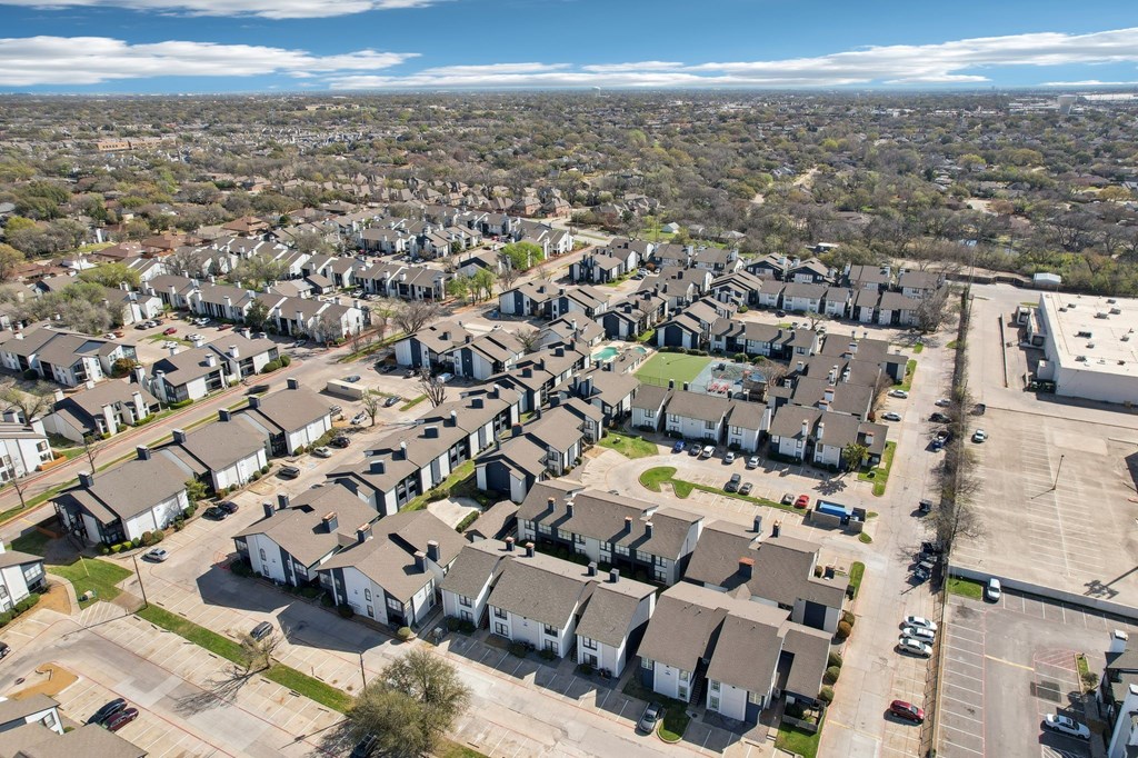 A bird's eye view of a residential area with houses and a parking lot.